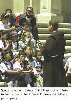 Priest on Bascilica steps explains history of the Mission Dolores to school kids.